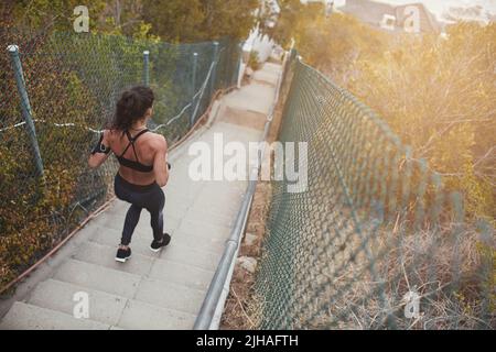Athletische junge Frau, die morgens die Treppe hinunter läuft. Sportliche junge Frau, die ein kräftiges körperliches Training absolviert. Stockfoto