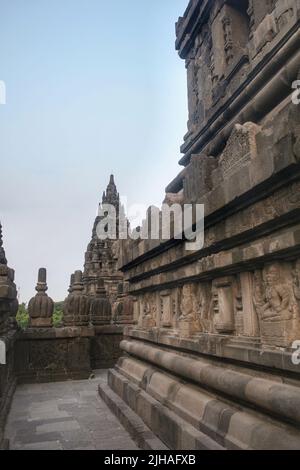 Das Innere eines Tempels im alten Prambanan Tempelkomplex mit klarem blauen Himmel Hintergrund. Leerer enger Korridor mit Reliefs an der Wand. Keine Personen. Stockfoto