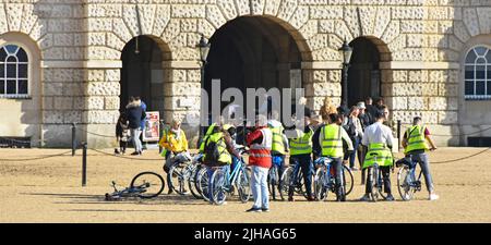 Eine Gruppe von Touristen, die auf einer Fahrradtour mit gut sichtbaren Jacken auf dem historischen Horse Guards Parade Ground für einen Fotostopp in London England, Großbritannien, unterwegs sind Stockfoto