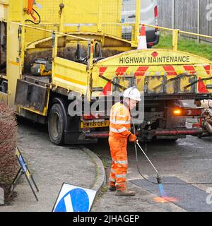 Highway Maintenance Mann bei der Arbeit an der Hitzeabdichtung Asphalt Straße Schlagloch Reparatur mit Gasflammenbrenner hohe Sichtbarkeit gelb Kipper LKW England Großbritannien Stockfoto