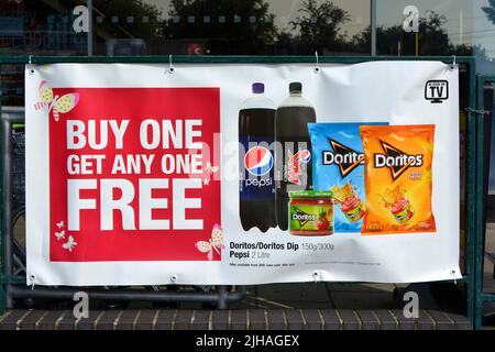 Banner auf Geländern vor dem örtlichen Supermarkt, der für „Buy One Get One“ wirbt, Sonderangebote für Speisen und Getränke (Datumspreise entfernt) England Großbritannien Stockfoto