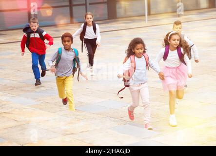 Team von positiven Schulkindern läuft im Rennen auf der Straße Stockfoto