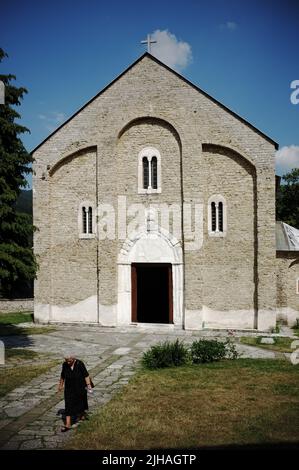 Eine ältere Frau in Schwarz verlässt die Kirche der Jungfrau von Studenica in Serbien Stockfoto
