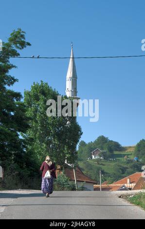 muslimische Frau in traditioneller Kleidung auf der Straße, die zur Moschee des Dorfes in Serbien führt Stockfoto