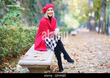 Lächelnde Frau mit Kaffeetasse im Park Stockfoto
