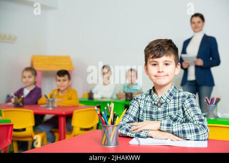 Preteen Junge Lernen im Klassenzimmer auf Hintergrund mit Klassenkameraden und Lehrer Stockfoto
