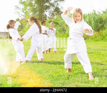 Kleines Mädchen im weißen Kimono Training Karate im Park Stockfoto