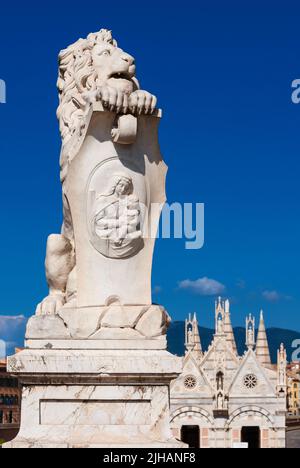 Eine Löwenstatue aus Marmor, die 1875 im historischen Zentrum von Pisa errichtet wurde, mit einer wunderschönen gotischen Kirche der heiligen Maria von Thorn im Hintergrund Stockfoto