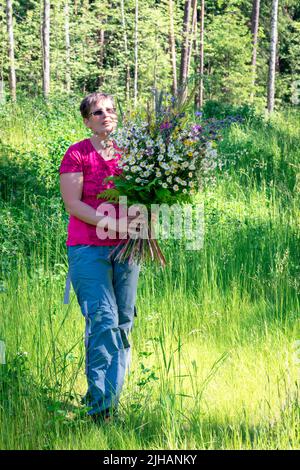 Frau mit riesigem Blumenstrauß, Porträt in voller Länge. Stockfoto