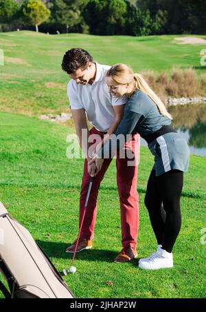 Frau Golfspielerin, die Mann zum Golfspielen austrainiert Stockfoto