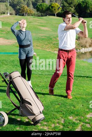 Golfer und Frau beobachten, wo der Ball Stockfoto