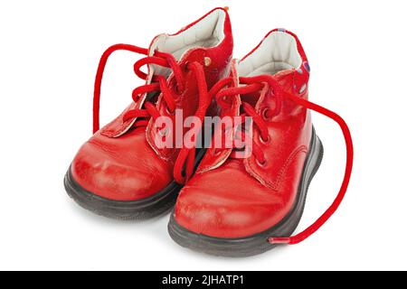 Abgenutzte rote Schnürsenkel im Kinderformat. Kinderschuhe mit Schnürsenkeln. Alte Stiefeletten für kleine Kinder. Datei enthält Beschneidungspfad. Stockfoto