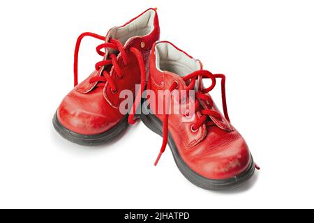 Abgenutzte rote Schnürsenkel im Kinderformat. Kinderschuhe mit Schnürsenkeln. Alte Stiefeletten für kleine Kinder. Datei enthält Beschneidungspfad. Stockfoto