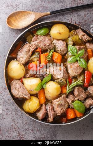 Köstlicher kroatischer Peka aus Kalbsfleisch mit saisonalem Gemüse und Kräutern aus der Nähe auf dem Tisch. Vertikale Draufsicht von oben Stockfoto