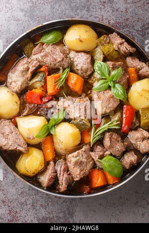 Nationale kroatische Lebensmittel Peka mit Fleisch und Gemüse über einem offenen Feuer in der Nähe auf dem Tisch gekocht. Vertikale Ansicht von oben Stockfoto