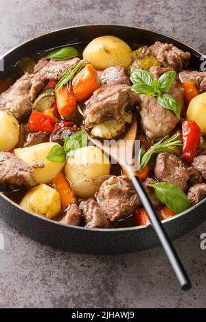 Nationale kroatische Lebensmittel Peka mit Fleisch und Gemüse über einem offenen Feuer in der Nähe auf dem Tisch gekocht. Vertikal Stockfoto