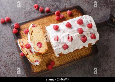 Brotscheiben aus Himbeer-Laib mit weißer Glasur in Nahaufnahme auf einem Holzbrett auf dem Tisch. Horizontale Ansicht von oben Stockfoto