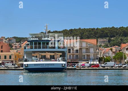 Argostili, Kefalonia, Griechenland - Juni 2022: Kleine Autofähre legt an der Uferpromenade von Argostili an, um Fahrzeuge zu laden Stockfoto