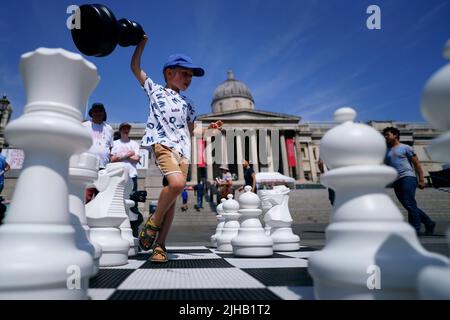 Finn Moriarty, 5 Jahre alt, bewegt riesige Schachfiguren während des ChessFest, dem größten eintägigen Schachereignis Großbritanniens, am Trafalgar Square im Zentrum von London. Bilddatum: Sonntag, 17. Juli 2022. Stockfoto