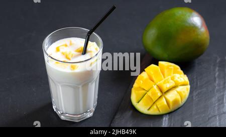 Milchgetränk auf schwarzem Hintergrund mit Mango. Ein klassischer Mango-Milchshake - Lassi. Ein traditionelles Getränk in Indien aus der Hitze Stockfoto