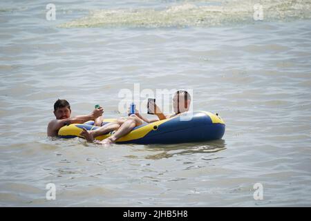 Die Menschen entspannen sich auf einer Lilo bei einem Drink im Meer bei Southend-on-Sea an der Themse-Mündung in Essex. Es wird erwartet, dass die Temperaturen am Sonntag in Zentralengland 31C Grad erreichen werden, bevor nächste Woche Rekordhochs erreicht werden. Bilddatum: Sonntag, 17. Juli 2022. Stockfoto