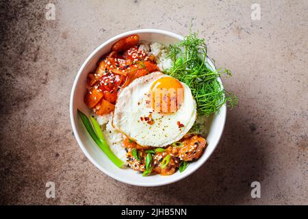 Bibimbap - Fleisch, Reis, Kimchi, Ei und Sprossen in einer weißen Schüssel, Draufsicht, Kopierraum. Traditionelle koreanische Küche. Stockfoto