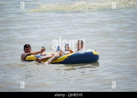 Die Menschen entspannen sich auf einer Lilo bei einem Drink im Meer bei Southend-on-Sea an der Themse-Mündung in Essex. Es wird erwartet, dass die Temperaturen am Sonntag in Zentralengland 31C Grad erreichen werden, bevor nächste Woche Rekordhochs erreicht werden. Bilddatum: Sonntag, 17. Juli 2022. Stockfoto