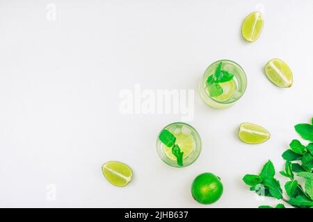 Sommerliches antioxidatives Getränk mit Limettenscheiben und Eis, verziert mit frischen Minzblättern. Erfrischendes kaltes Getränk. Grauer Hintergrund. Draufsicht, flach liegend, Polizist Stockfoto