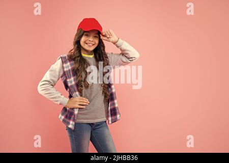 Happy Kid mit lockigem Haar in Mütze auf rosa Hintergrund mit Copy Space, Fashionista Stockfoto