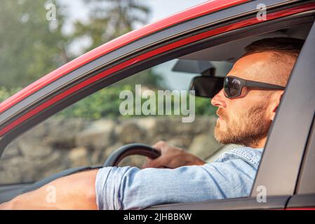 Ein Mann mit einem Lächeln auf dem Gesicht fährt ein Auto. Stockfoto