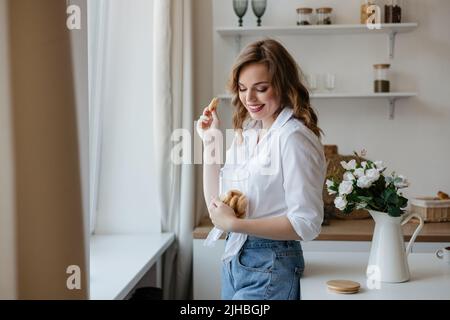 Hübsches Mädchen, das in der Küche Kekse isst Stockfoto