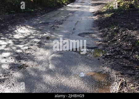 Gefährliche Schlaglöcher auf einer Landstraße in Großbritannien Stockfoto