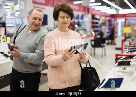 Europäische Ehegatten im reifen Alter wählen ein Tablet und ein Mobiltelefon Stockfoto