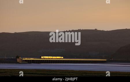 Network Rail Infrastructure überwacht den Zug, der das Arnside Viadukt auf der malerischen Bahnlinie der Cumbrian Coast überquert, mit einem goldenen Glanz bei Sonnenuntergang Stockfoto