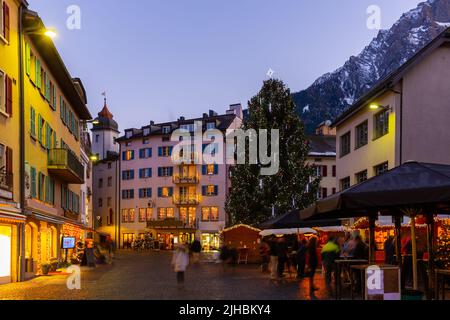 Abendansicht der Brig-Glis Straße mit Weihnachtsbaum auf dem Hintergrund der Alpengipfel Stockfoto