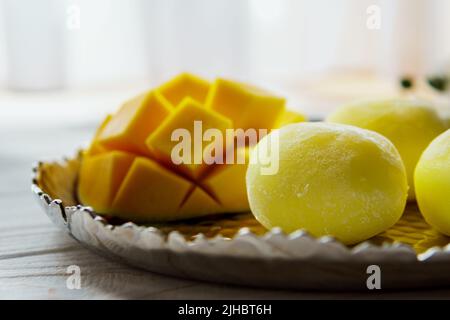 Leckeres Dessert Mochi mit Mangofrucht auf Holzhintergrund, Nahaufnahme. Traditionelles japanisches Reiskuchen-Dessert Stockfoto