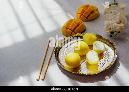 Leckeres Dessert Mochi mit Mangofrucht auf grauem Hintergrund, Nahaufnahme. Traditionelles japanisches Reiskuchen-Dessert Stockfoto
