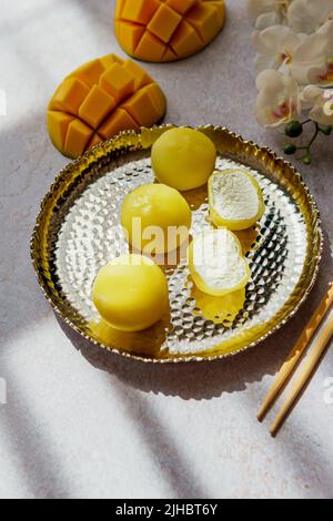 Leckeres Dessert Mochi mit Mangofrucht auf grauem Hintergrund, Nahaufnahme. Traditionelles japanisches Reiskuchen-Dessert Stockfoto