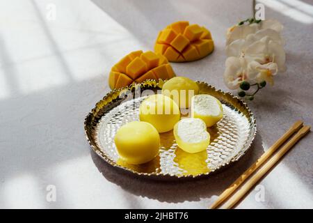 Leckeres Dessert Mochi mit Mangofrucht auf grauem Hintergrund, Nahaufnahme. Traditionelles japanisches Reiskuchen-Dessert Stockfoto