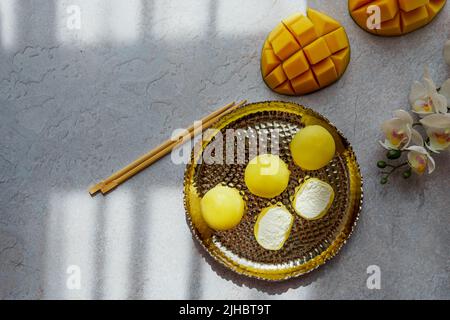 Leckeres Dessert Mochi mit Mangofrucht auf grauem Hintergrund, Nahaufnahme. Traditionelles japanisches Reiskuchen-Dessert Stockfoto