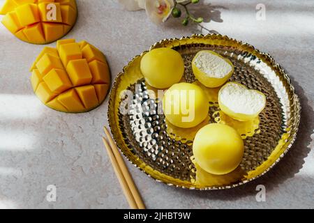 Leckeres Dessert Mochi mit Mangofrucht auf grauem Hintergrund, Nahaufnahme. Traditionelles japanisches Reiskuchen-Dessert Stockfoto