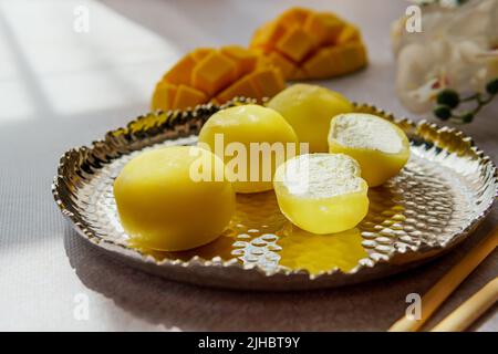 Leckeres Dessert Mochi mit Mangofrucht auf grauem Hintergrund, Nahaufnahme. Traditionelles japanisches Reiskuchen-Dessert Stockfoto