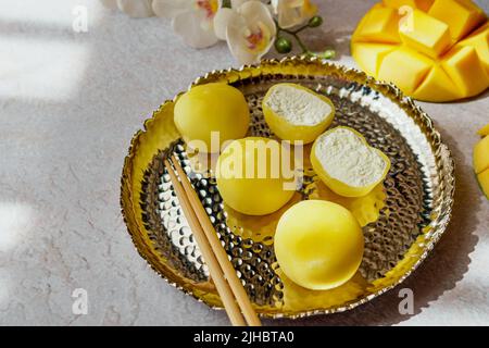 Leckeres Dessert Mochi mit Mangofrucht auf grauem Hintergrund, Nahaufnahme. Traditionelles japanisches Reiskuchen-Dessert Stockfoto