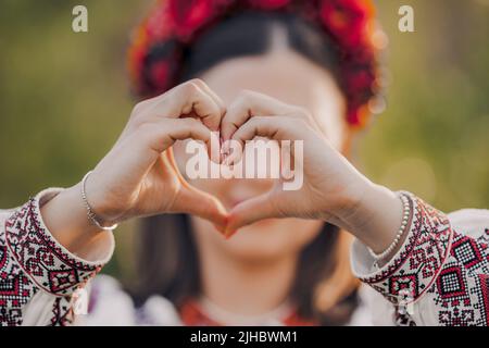 Ukrainische Frau in der traditionellen Stickerei vyschywanka Kleid, das Zeichen der Form Herz. Ukraine, Freiwilligenarbeit, Spendenhilfe und Liebeskonzept. Stockfoto