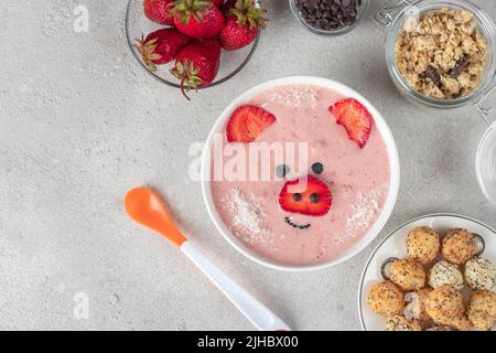 Fun Food für Kinder - Smoothie-Schale in Form lustiges Ferkel, mit Erdbeeren, Müsli, Schokolade und knusprigen Kugeln, Draufsicht Stockfoto