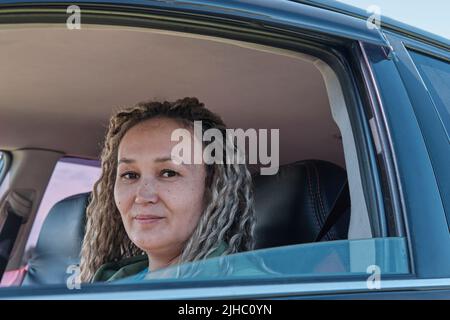 Nahaufnahme Porträt von niedlichen lächelnden mittleren Alters asiatische Frau in offenen Autofenster. Stockfoto