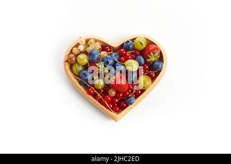 Beeren mischen sich in einer herzförmigen Schüssel auf weißem Hintergrund Stockfoto