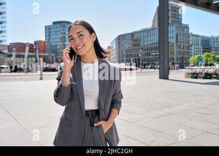 Junge asiatische Geschäftsfrau trägt Anzug, der auf der Straße der Stadt steht und telefoniert. Stockfoto