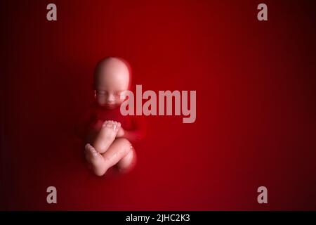 Abtreibungskonzept. Babypuppe im roten Blut sieht aus wie eine Abtreibung. Stockfoto