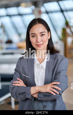 Junge, selbstbewusste asiatische Geschäftsfrau im Büro. Vertikales Hochformat Stockfoto